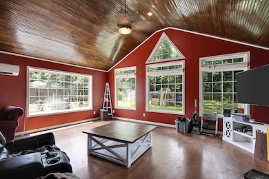 Living area featuring a wall unit AC, wooden ceiling, vaulted ceiling, healthy amount of natural light, and wood-type flooring