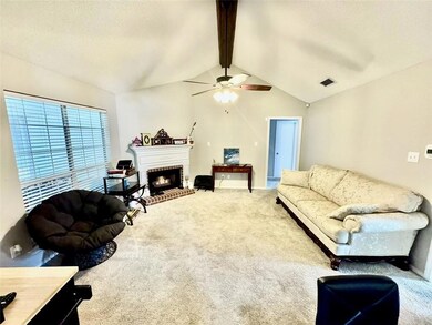 Living room with carpet, a fireplace, a textured ceiling, and ceiling fan