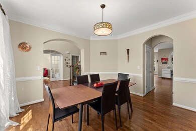 Dining room featuring arched walkways, ornamental molding, and wood finished floors