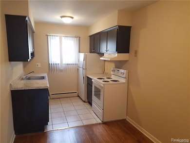 Kitchen with white range with electric cooktop, light countertops, a baseboard radiator, and exhaust hood