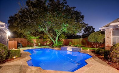 Backyard oasis at twilight features a sparkling po