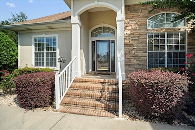 Entrance to property featuring roof with shingles, stone siding, and stucco siding