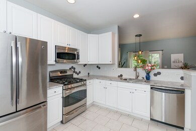 Welcome to your new eat in kitchen; newer white cabinets, sink, Quartzite (natural stone) counters, backsplash