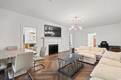 Living area featuring a fireplace with raised hearth, an office area, a chandelier, and a textured ceiling
