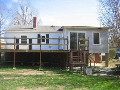 Rear view of home showing off the large deck and the sliding patio doors from the enclosed porch.