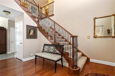 Designated entry foyer with iron spindle staircase and gleaming hardwood floors.