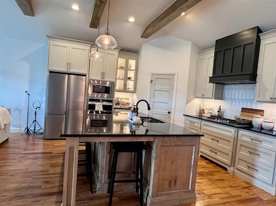 Kitchen featuring appliances with stainless steel finishes, dark countertops, decorative backsplash, a kitchen breakfast bar, and light wood-style flooring