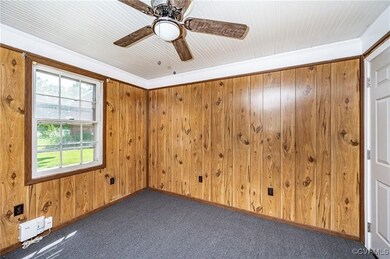 Carpeted empty room with crown molding, wood walls