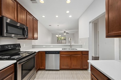 Kitchen featuring stainless steel appliances, backsplash, recessed lighting, decorative light fixtures, and brown cabinetry