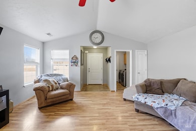 Living room featuring vaulted ceiling, light wood-style floors, separate washer and dryer, and ceiling fan