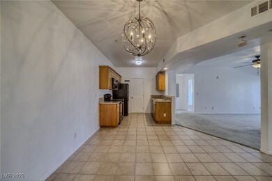 Kitchen with light tile patterned floors, brown cabinets, light countertops, and black appliances