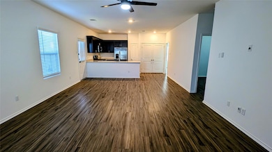 Unfurnished living room featuring dark wood-style floors, a ceiling fan, and recessed lighting