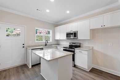 Kitchen with white cabinets, appliances with stain