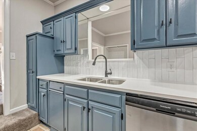 Kitchen with stainless steel dishwasher, tasteful backsplash, crown molding, blue cabinets, and light stone countertops