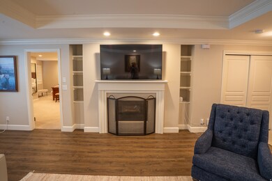Living area featuring crown molding, a fireplace, a tray ceiling, wood finished floors, and recessed lighting