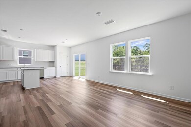 Unfurnished living room featuring healthy amount of natural light, wood finished floors, and baseboards
