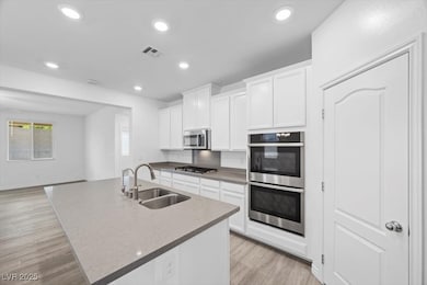 Kitchen featuring white cabinets, a center island with sink, stainless steel appliances, recessed lighting