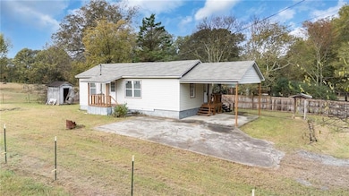 Manufactured / mobile home with a patio, view of scattered trees, and a shingled roof
