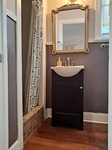 Full bathroom with wood finished floors, vanity, 