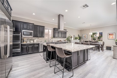 10 ft ceilings! Kitchen featuring crown molding and luxury vinyl plank flooring, a breakfast bar, custom cabinets, massive Electrolux fridge/freezer, built in appliances, double ovens, a giant granite center island with cooktop, hood and extra cabinets underneath and a walk in pantry.
