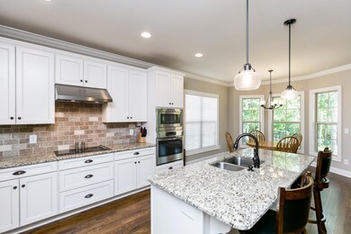 Tiled backsplash, cooktop, and built in wall oven.  