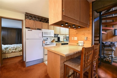 Kitchen featuring dark carpet, wooden walls, kitch