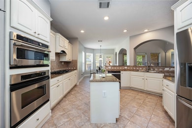 Updated kitchen boasts built-in stainless steel microwave and ovens, granite countertops, an island, and a convenient breakfast area nearby.