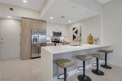 Kitchen showcasing sleek modern cabinetry, stainless steel appliances, and a waterfall island topped with elegant white quartz.