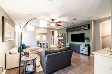 Living area featuring arched walkways, wood finished floors, and a ceiling fan