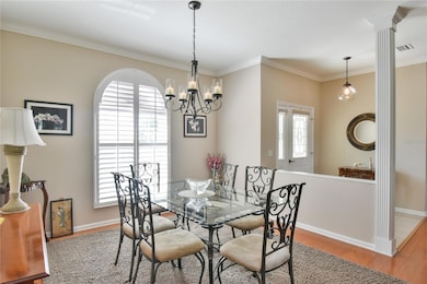 Dining room with new lighting fixture and crown molding and hardwood floors.