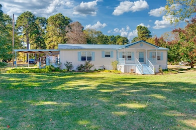 Rear view of house featuring a porch, a carport, a lawn, and a metal roof