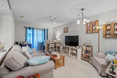 Living area featuring wood finished floors, a textured ceiling, ceiling fan, and a chandelier
