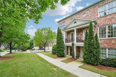 View of property exterior featuring brick siding, a balcony, and a yard