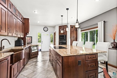 Kitchen featuring black appliances, a sink, healthy amount of natural light, a breakfast bar, and recessed lighting