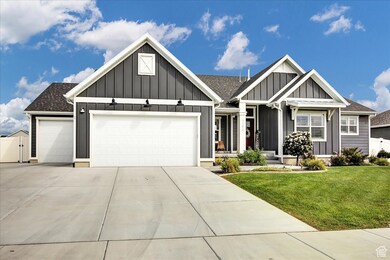 View of front of home with board and batten siding, an attached garage, driveway, and a gate