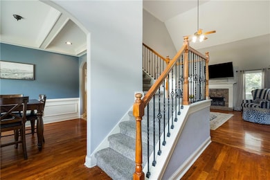 Stairs with arched walkways, a ceiling fan, wood finished floors, a fireplace, and wainscoting