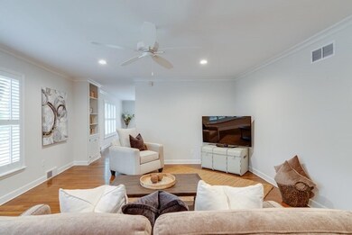 Living area with baseboards, visible vents, crown 
