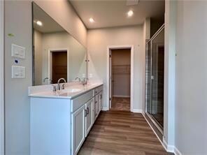 Bathroom with double vanity, wood finished floors, recessed lighting, and an enclosed shower