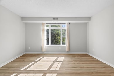 Inviting living room with sun-filled windows and warm flooring—perfect for relaxing or entertaining.