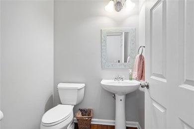 Bathroom with toilet, wood finished floors, and baseboards