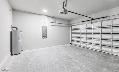 Garage with water heater, electric panel, and a ga