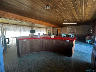 Kitchen featuring tile countertops, decorative light fixtures, open floor plan, wooden ceiling, and brick wall