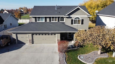 Traditional home with board and batten siding, concrete driveway, an attached garage, roof with shingles, and stone siding