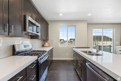 Kitchen featuring stainless steel appliances, healthy amount of natural light, dark wood-style floors, decorative backsplash, and recessed lighting