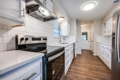 Kitchen featuring under cabinet range hood, a sink