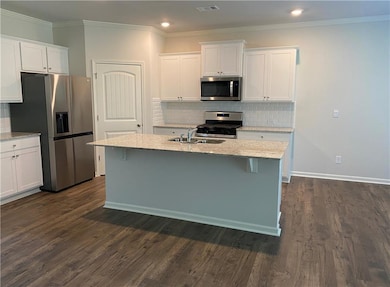 Kitchen featuring appliances with stainless steel finishes, white cabinetry, tasteful backsplash, ornamental molding, and recessed lighting