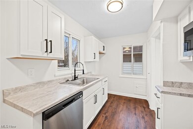 Kitchen with dark hardwood / wood-style flooring, dishwasher, sink, and white cabinetry