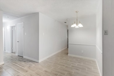 Empty room with a textured ceiling, a chandelier, crown molding, and wood finish floors