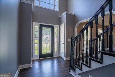 Foyer featuring a towering ceiling, stairs, and wood finished floors