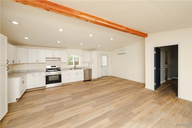 Kitchen with light countertops, white cabinets, st